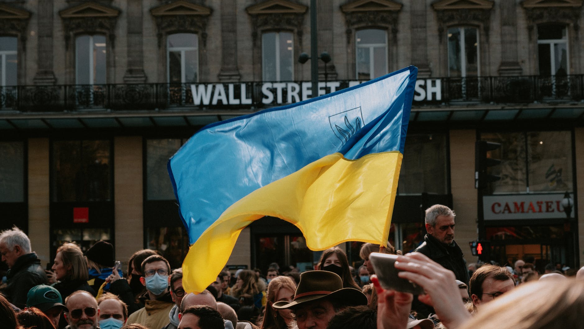 blue and yellow ukrainian flag waving above crowd of people