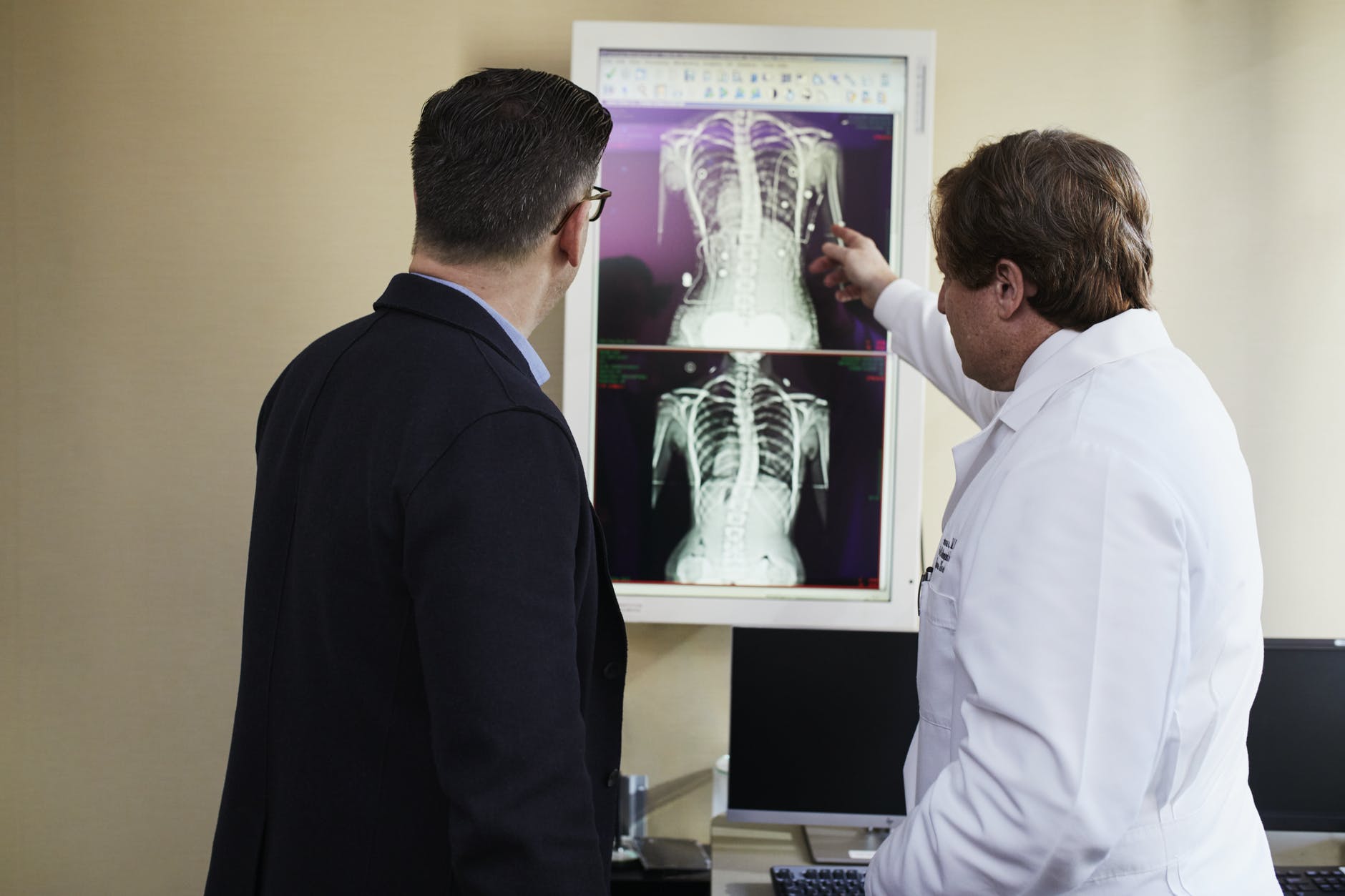 doctor pointing x ray result beside man wearing black suit