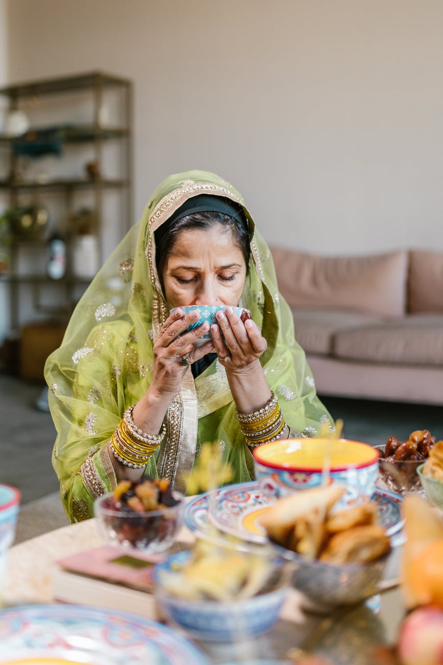 woman in green hijab drinking on a ceramic bowl