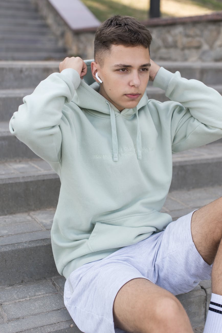 portrait of teenager with wireless earphones sitting on stairs