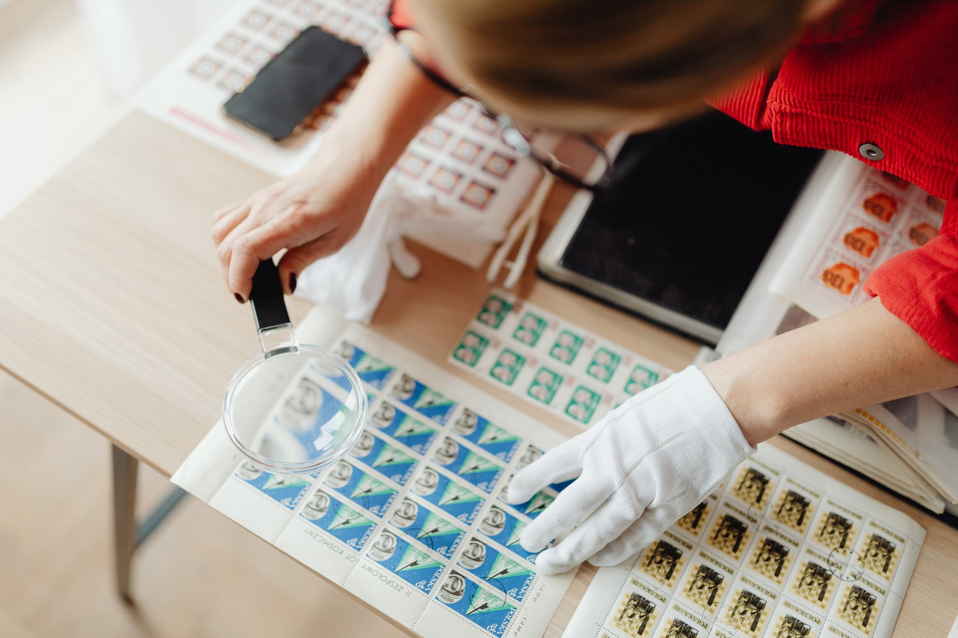 a woman using a magnifying glass on postage stamps