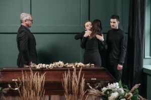 a group of people in black clothing grieving near a coffin