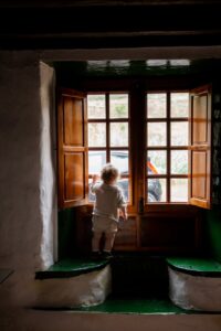 adorable toddler standing alone near window in rural interior house