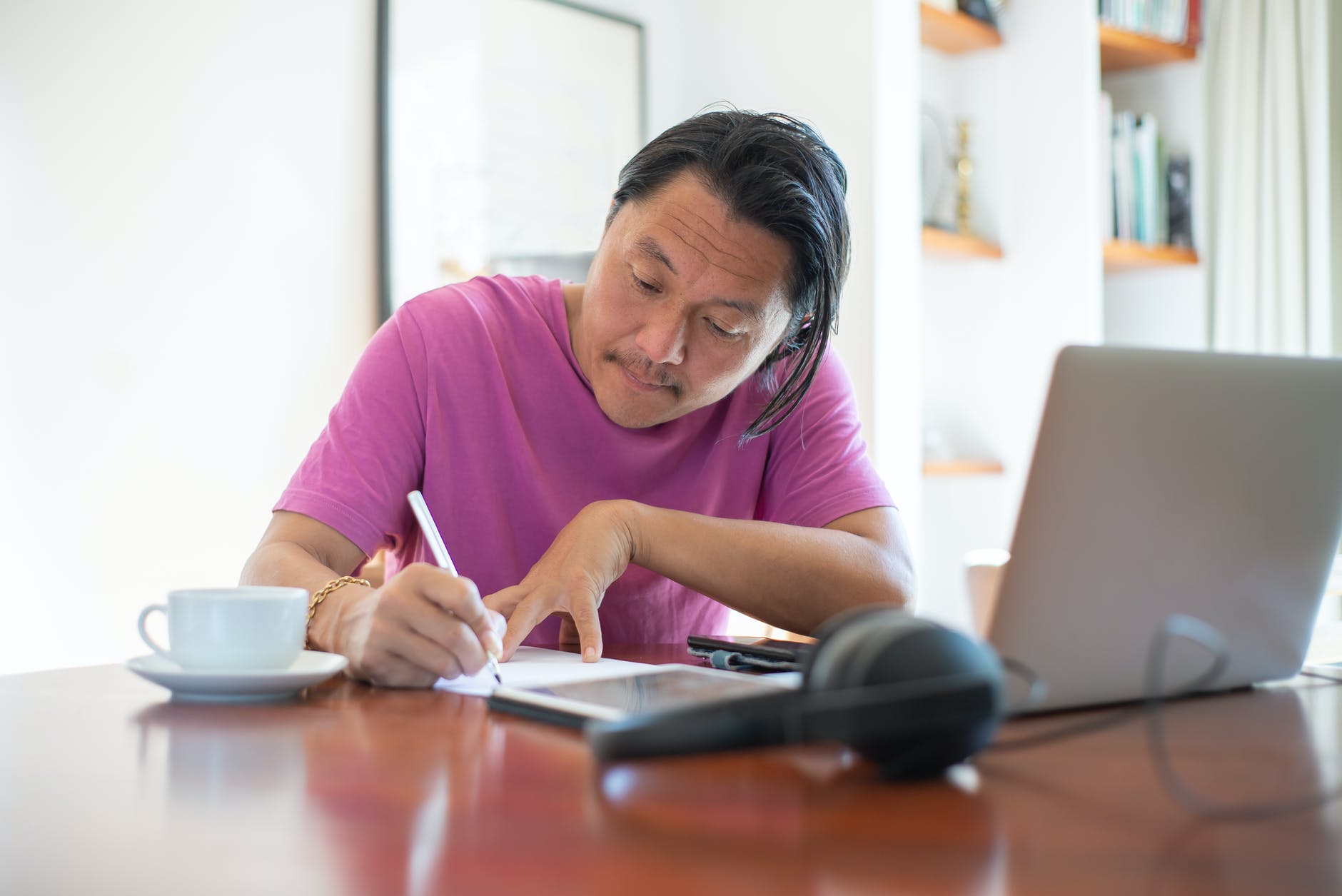 a man in pink shirt writing on the table