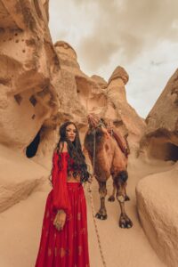 woman in red dress with camel on desert