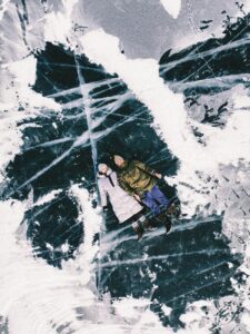 couple in winter clothes laying on big flat rock covered with snow