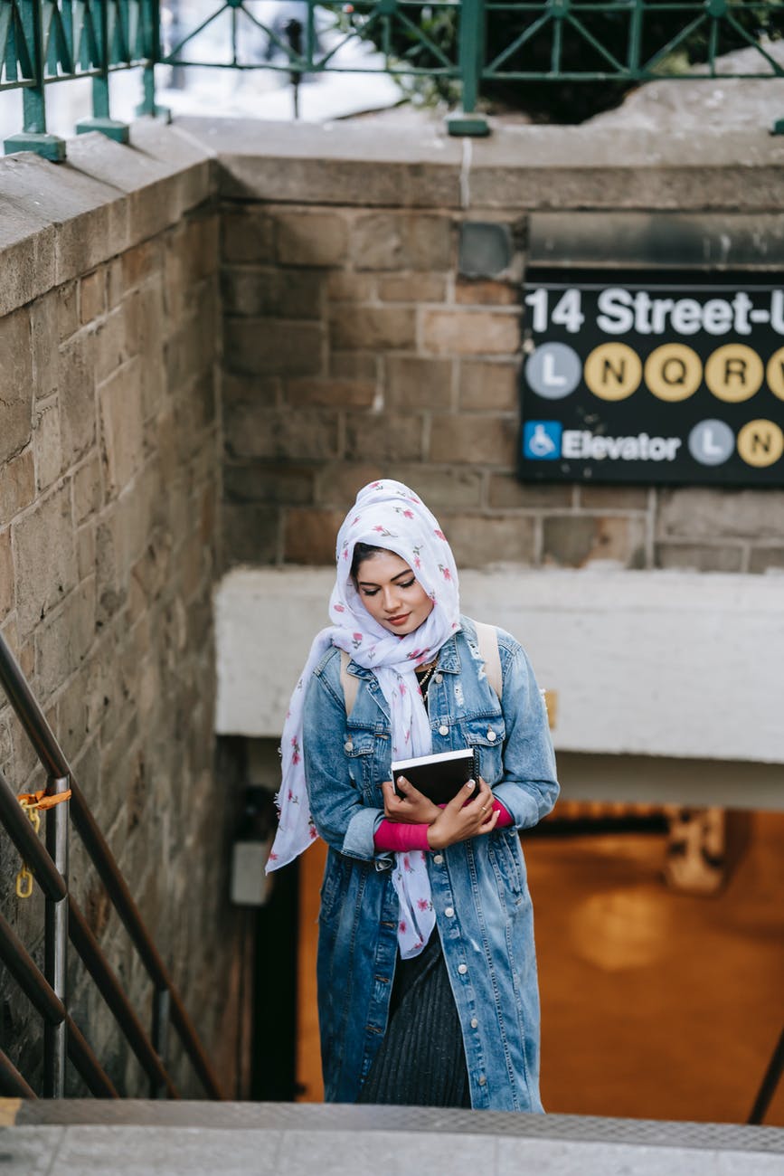 young muslim lady walking upstairs from subway in megapolis