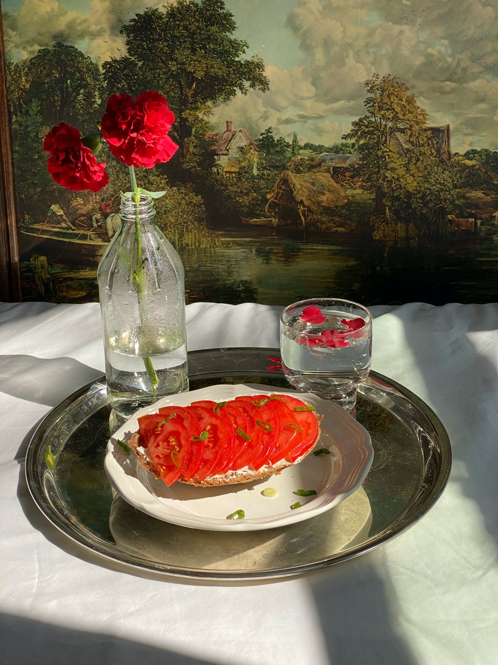 tray with sandwich with tomatoes near glass and flower