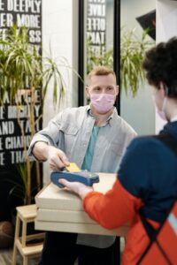 man wearing a face mask paying for pizza delivery