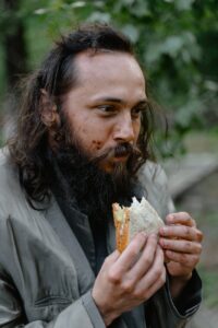 a man in gray jacket eating a bread
