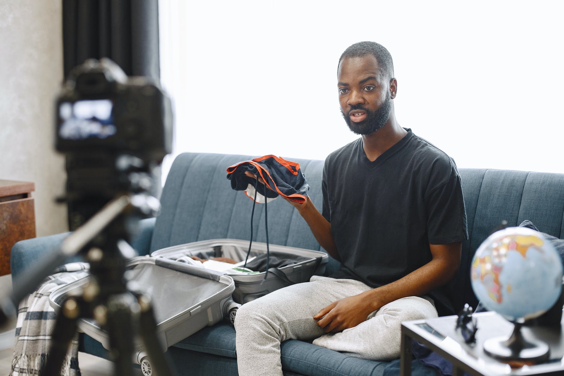 male vlogger sitting on a sofa while shooting a video