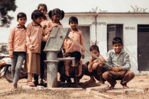 children standing next to manual water pump