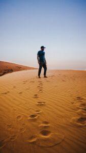 anonymous man enjoying desert views standing on sandy dunes