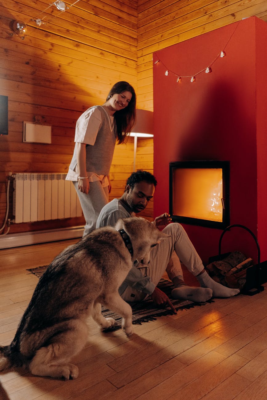 couple sitting near fireplace with their dog