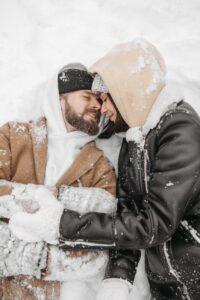 close up shot of a romantic couple lying on snow covered ground