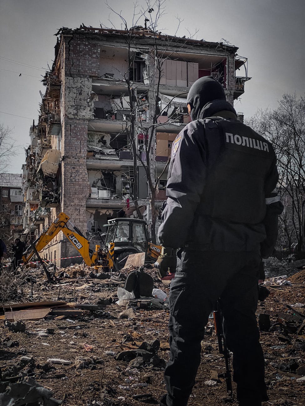 policeman beside destruction of a residential building in kyiv