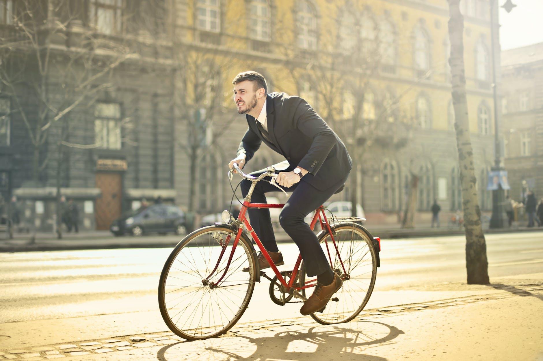 man in black suit riding bicycle down the street