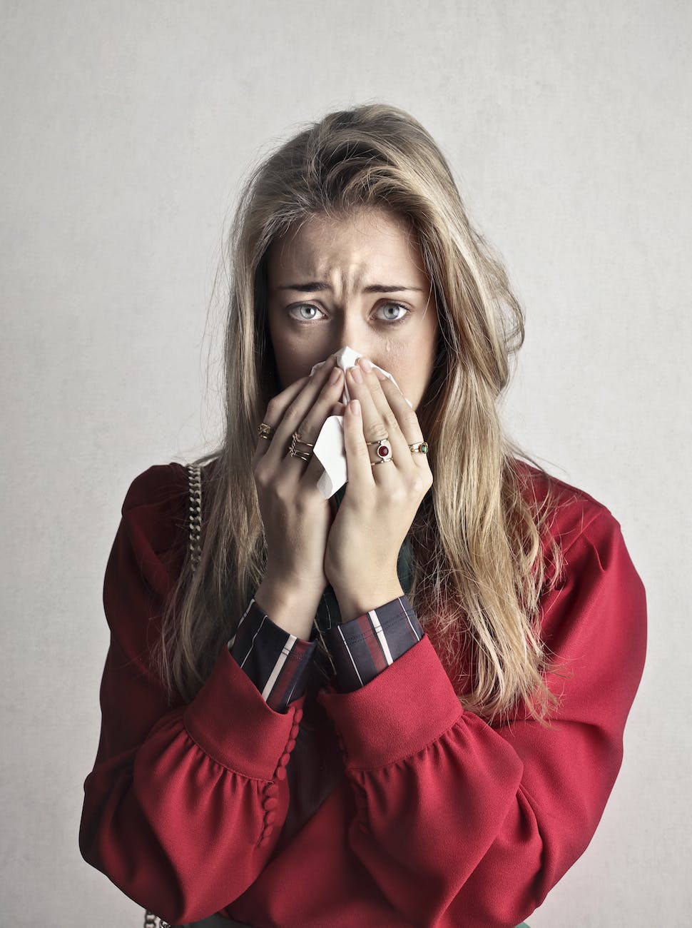 photo of crying woman in red long sleeve shirt blowing her nose