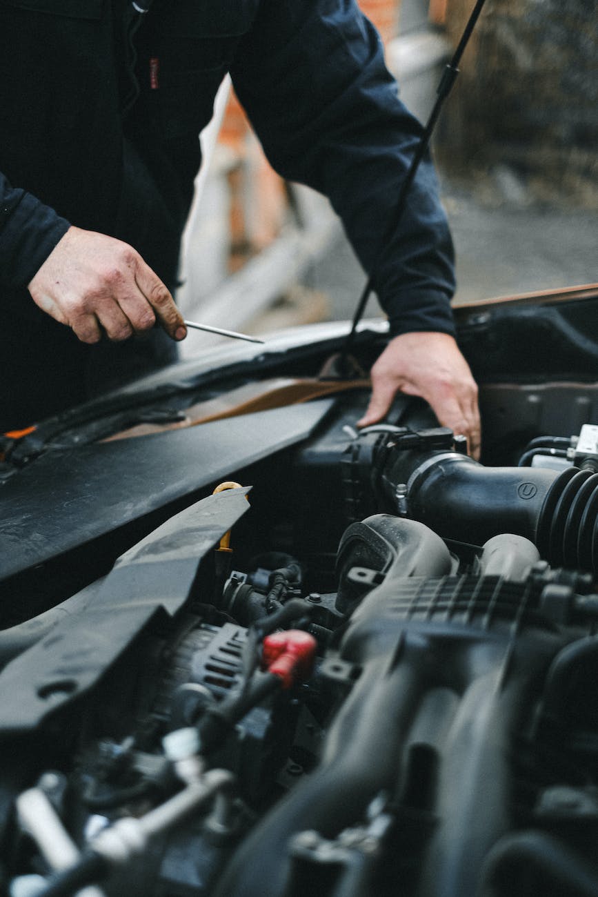 person in black long sleeves repairing the car engine