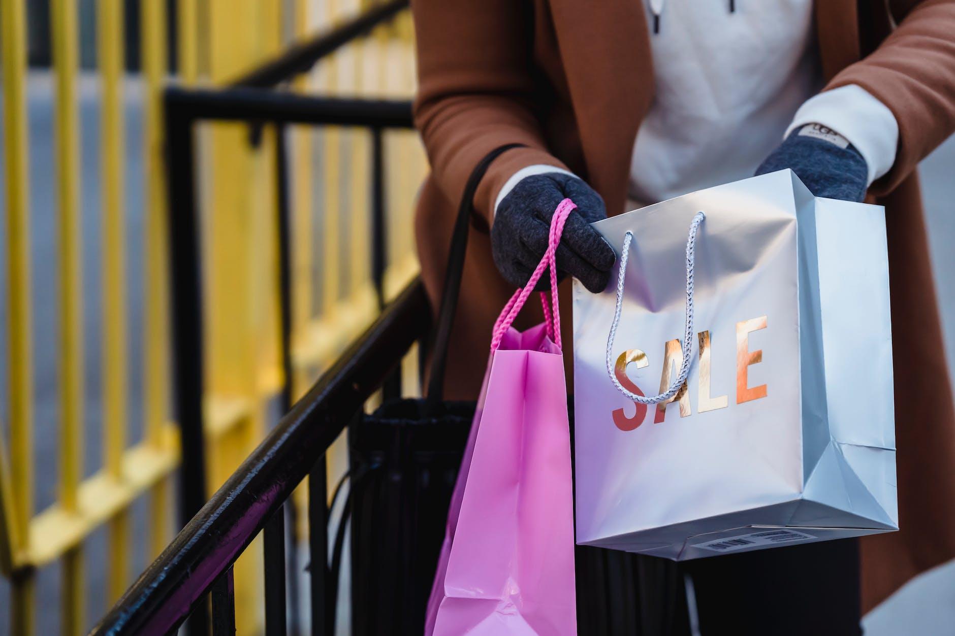 crop faceless woman looking in shopping bags on spring street