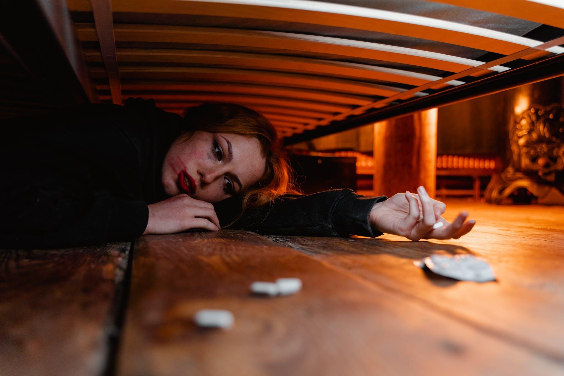 an emotional woman lying under the bed