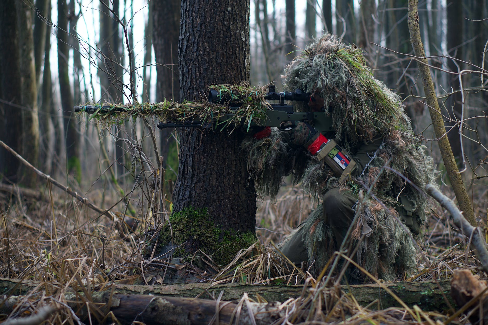 a soldier sniper aiming though the rifle scope in forest