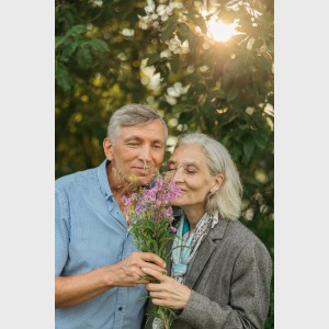 elderly couple smelling a flower
