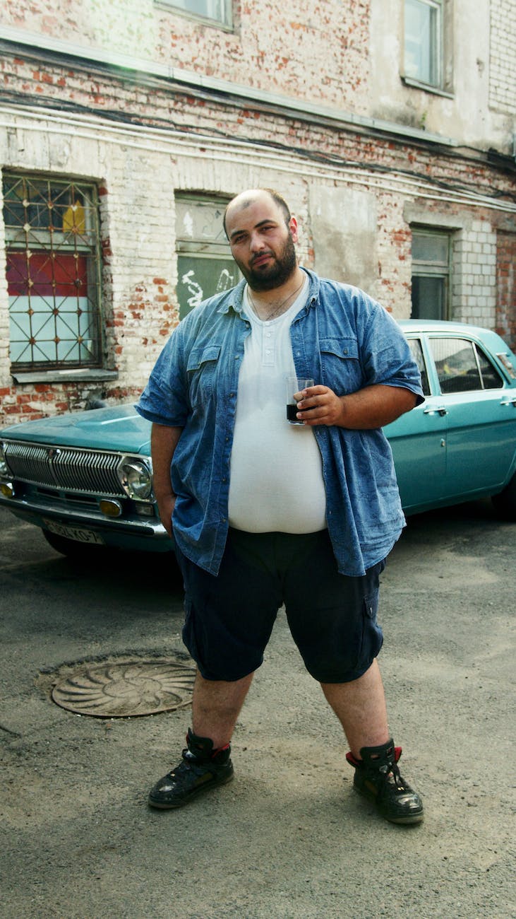 man standing near parked green car