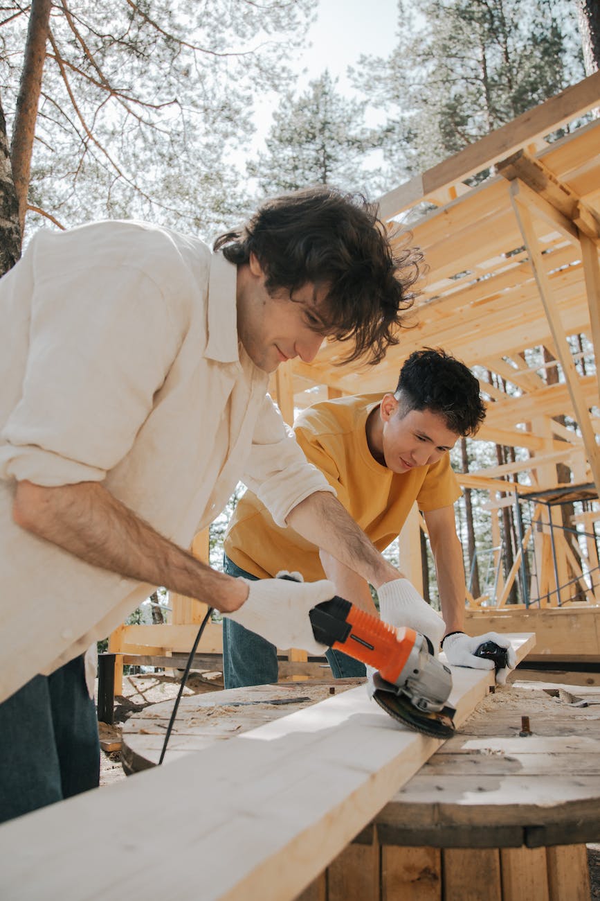 two men cutting a wooden plank