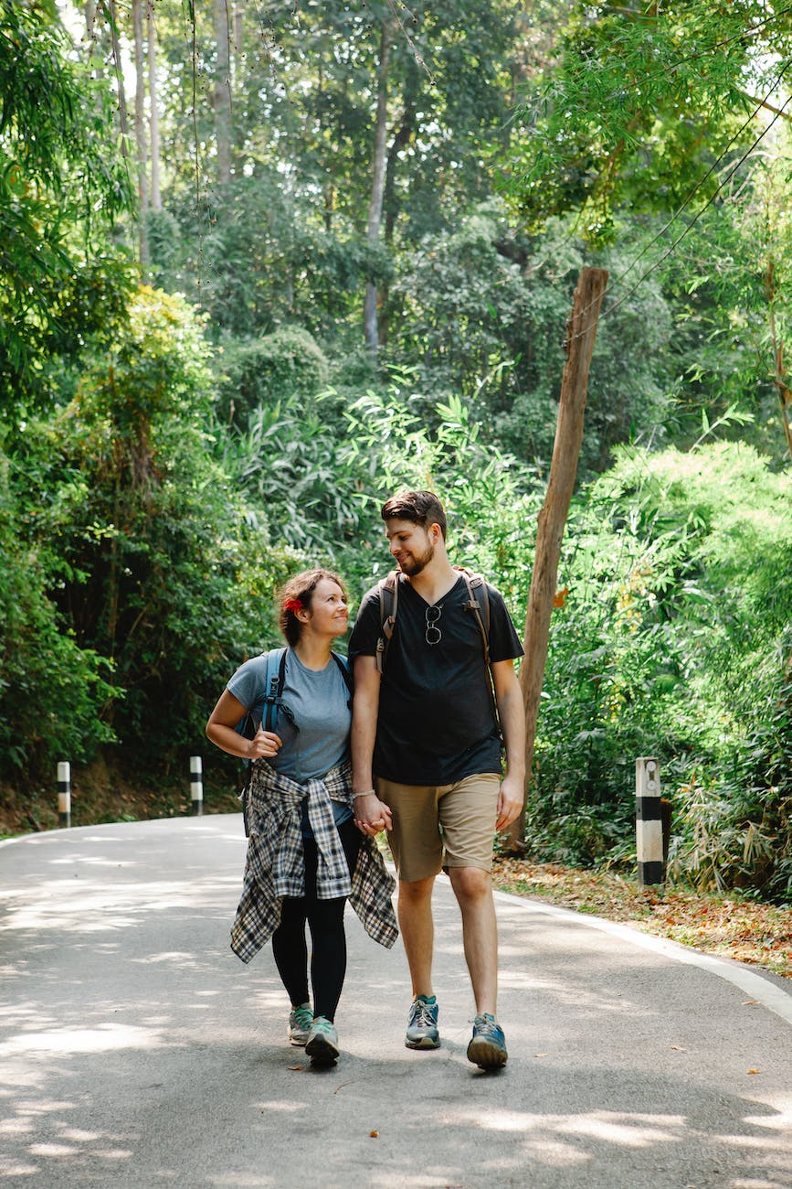 romantic couple holding hands and walking on path in jungle