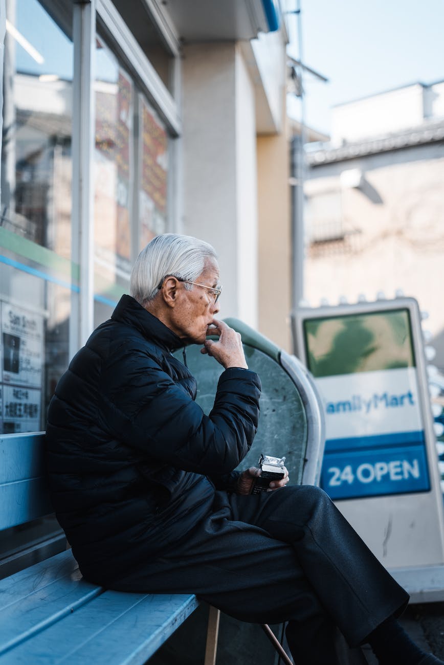 man in black jacket sitting on wooden bench