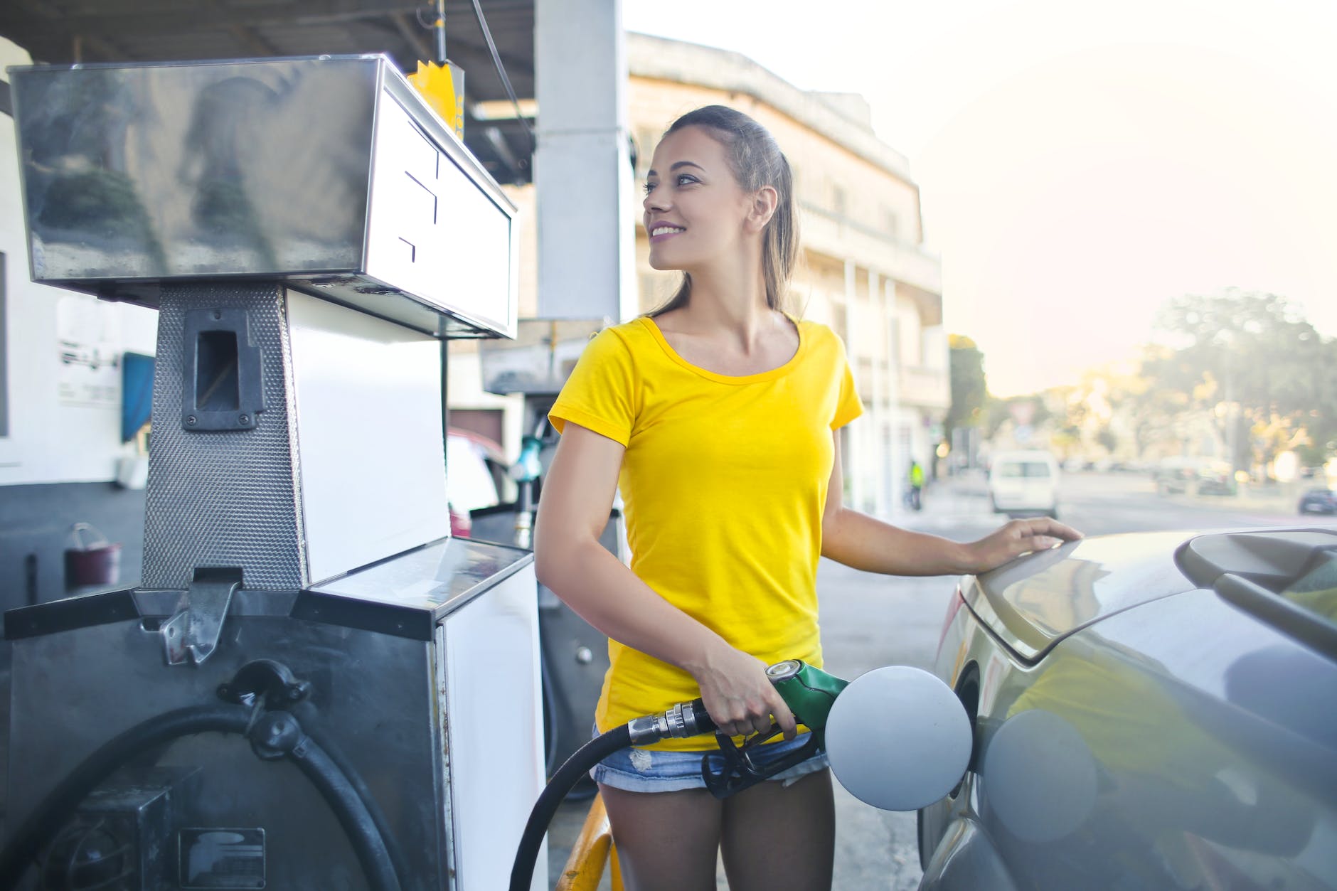 woman in yellow shirt while filling up her car with gasoline