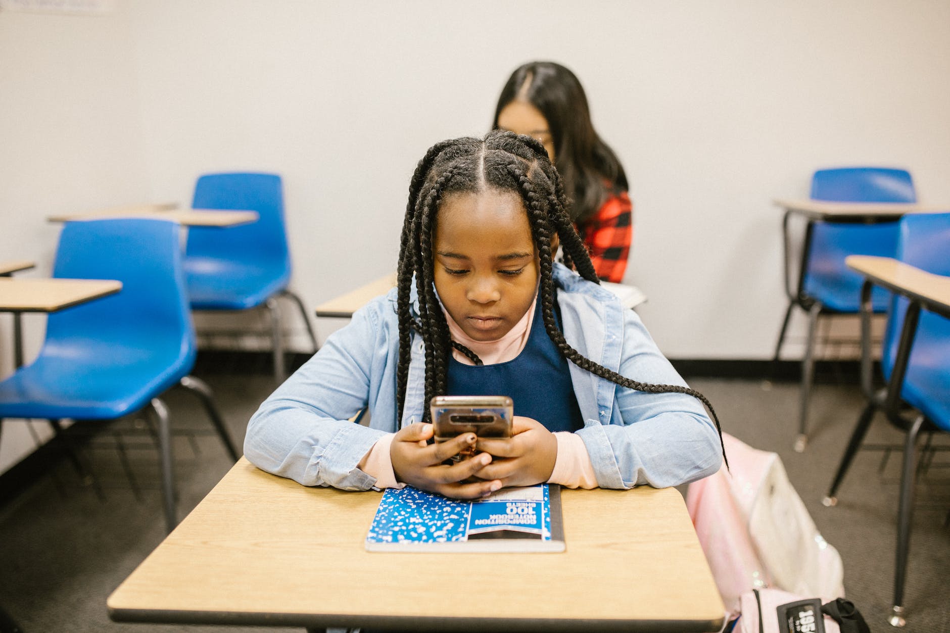 girl sitting on her desk while using her smartphone
