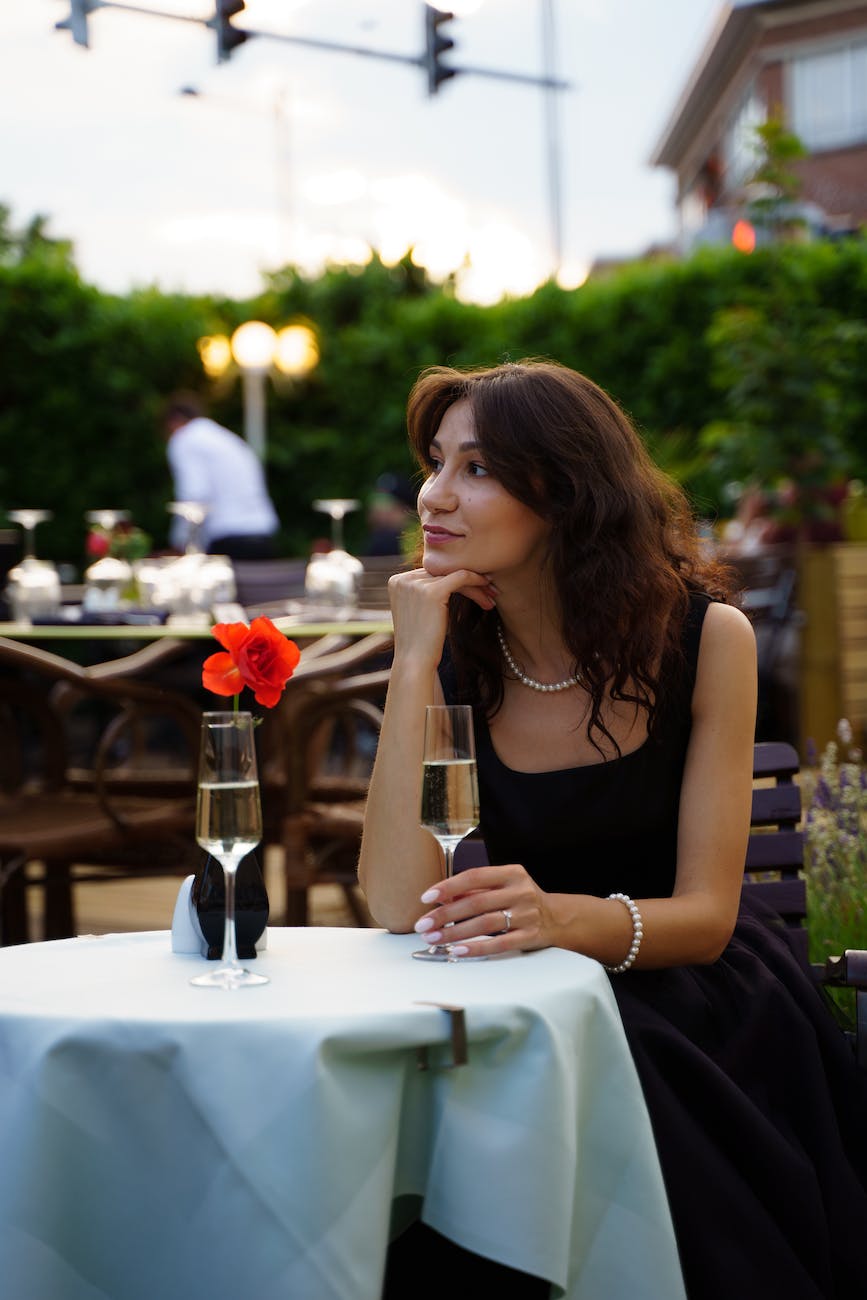 beautiful woman in a black dress sitting at an outdoor restaurant table