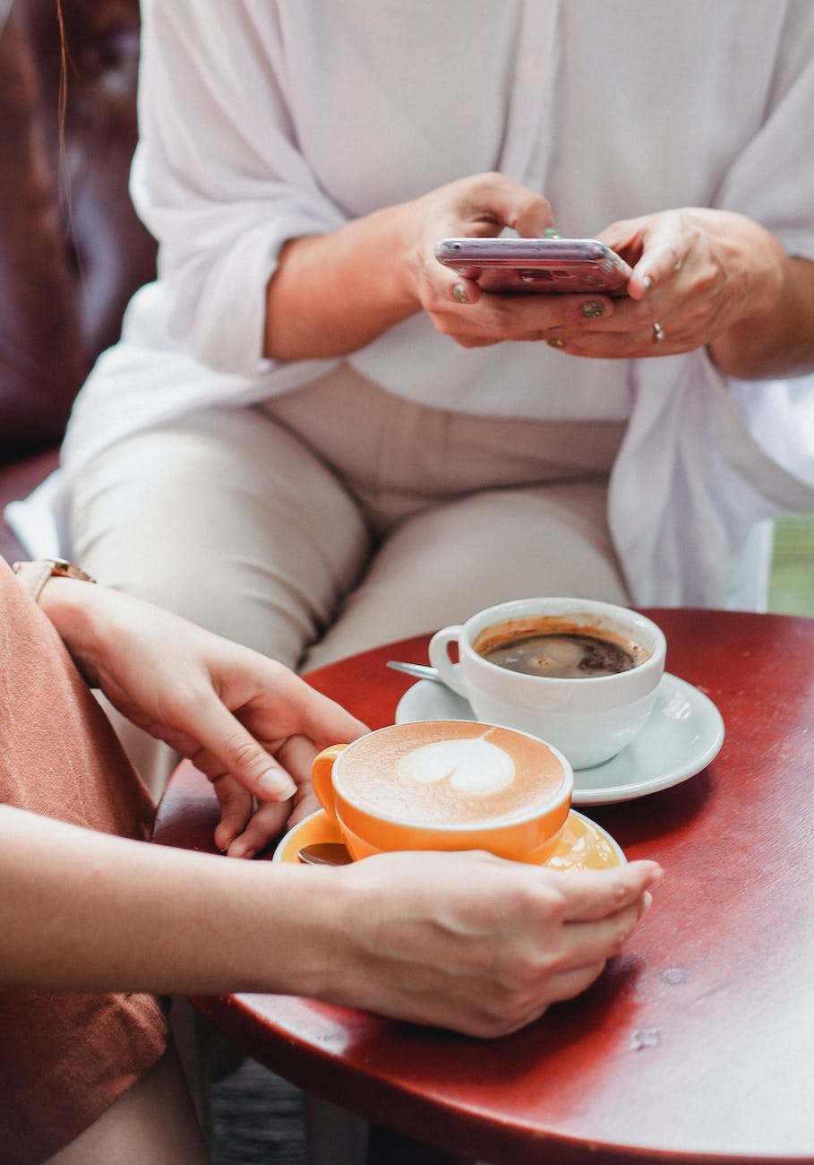 friends sitting at table with coffee in cafe