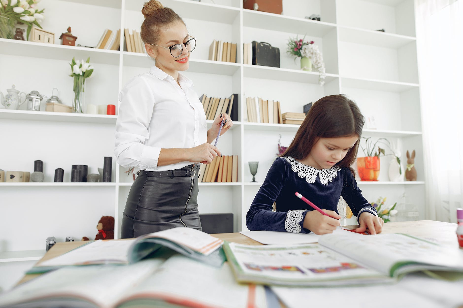 serious schoolgirl with tutor doing homework
