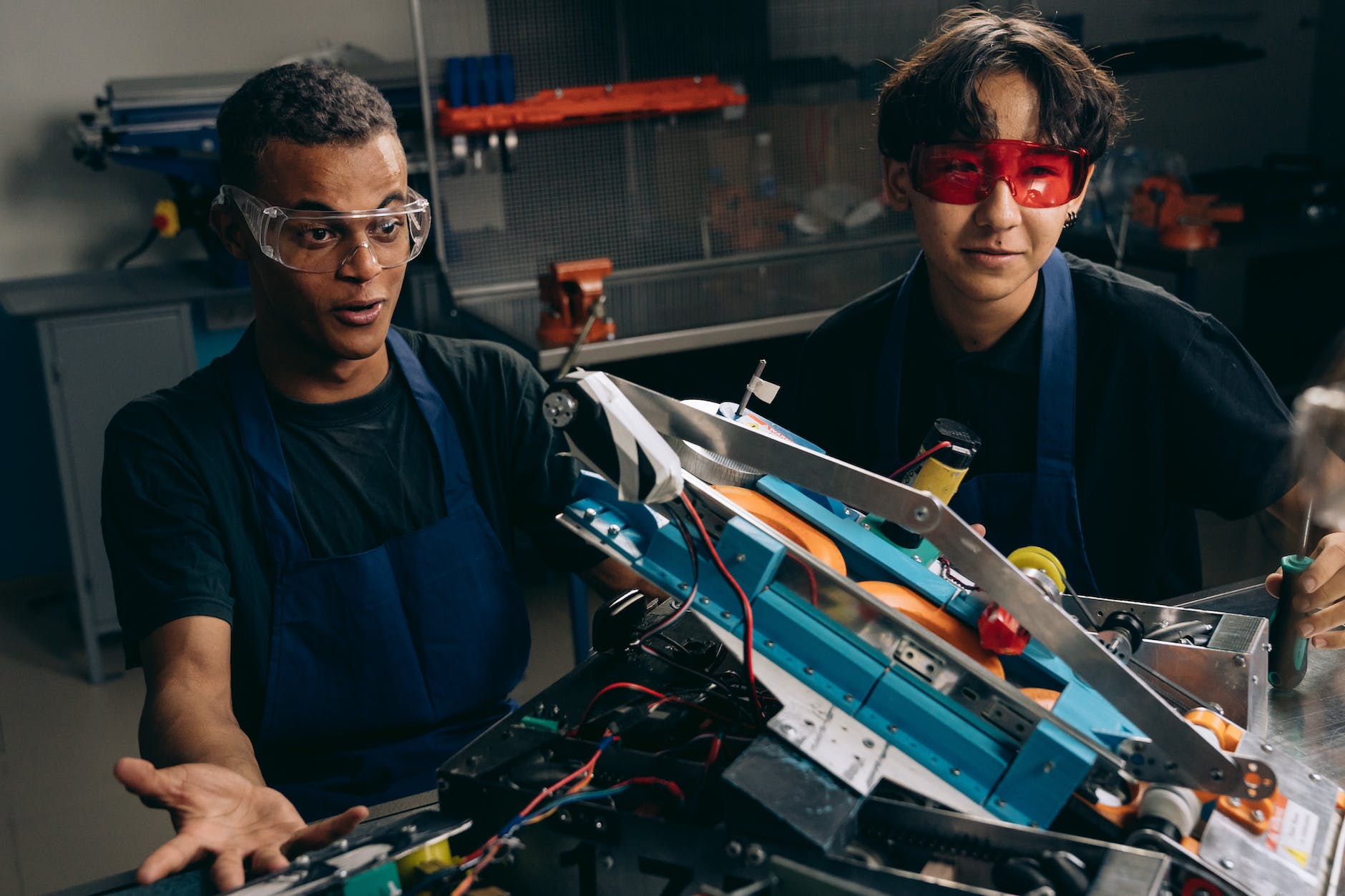 man in blue jacket wearing sunglasses holding black and red corded device