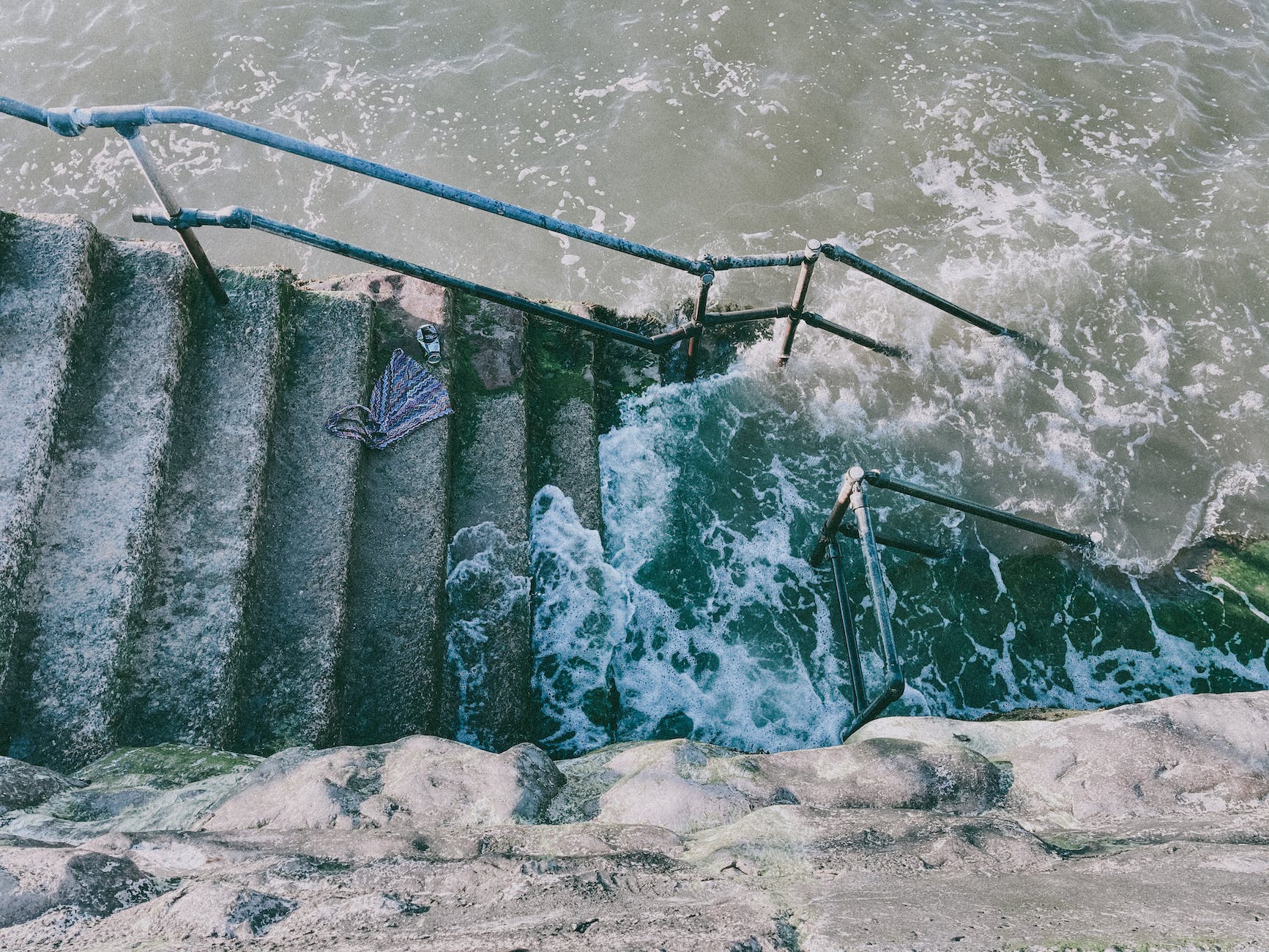 old staircase between fence and stormy sea with foam