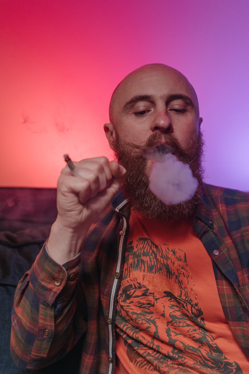 a bald man blowing smoke