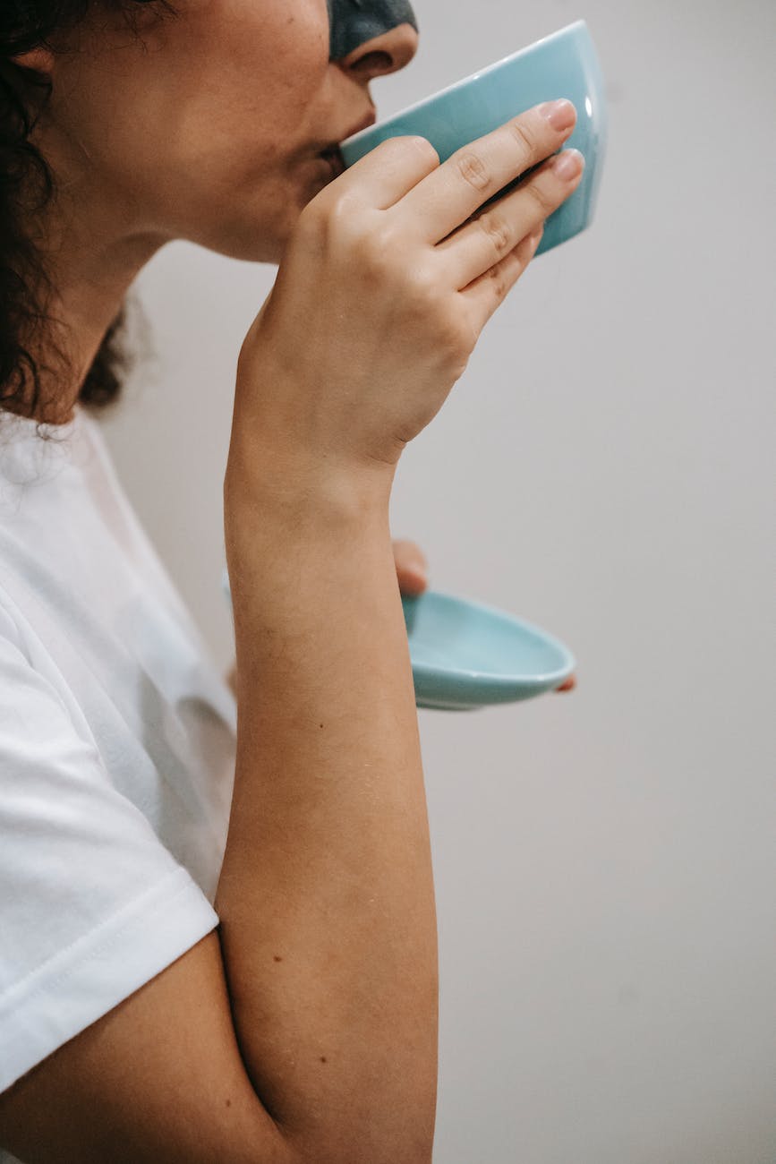 woman drinking hot beverage from ceramic cup