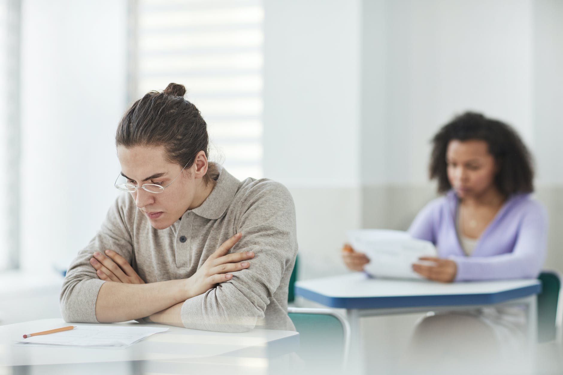 selective focus photo of a man with eyeglasses looking at his test paper