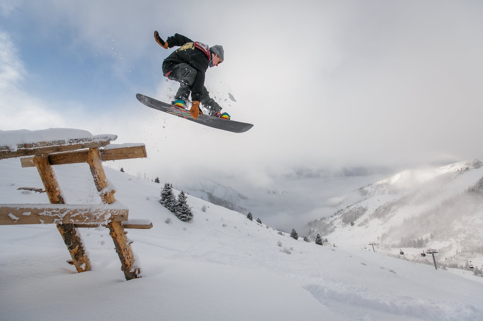 man in black snowboard with binding performs a jump