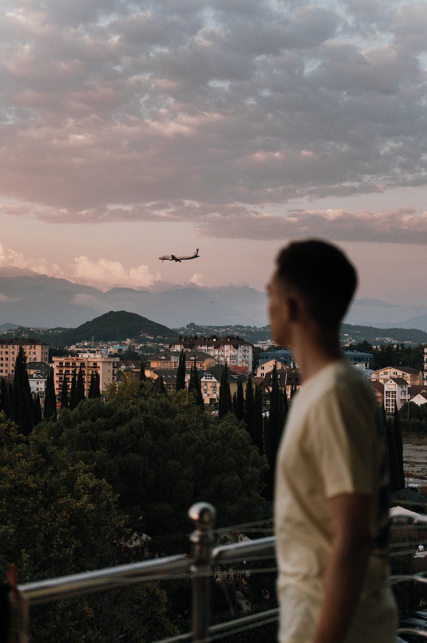 man looking at flying airplane