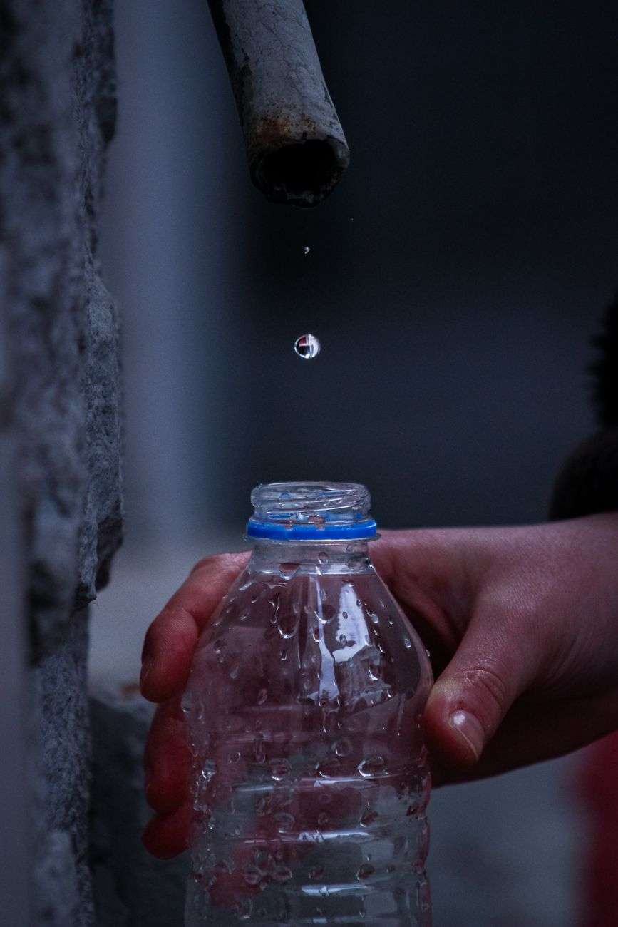 hand collecting water droplets into a bottle