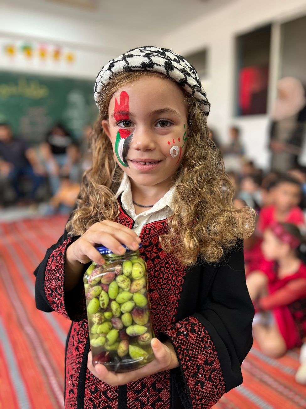 young girl holding pickles at cultural event in gaza
