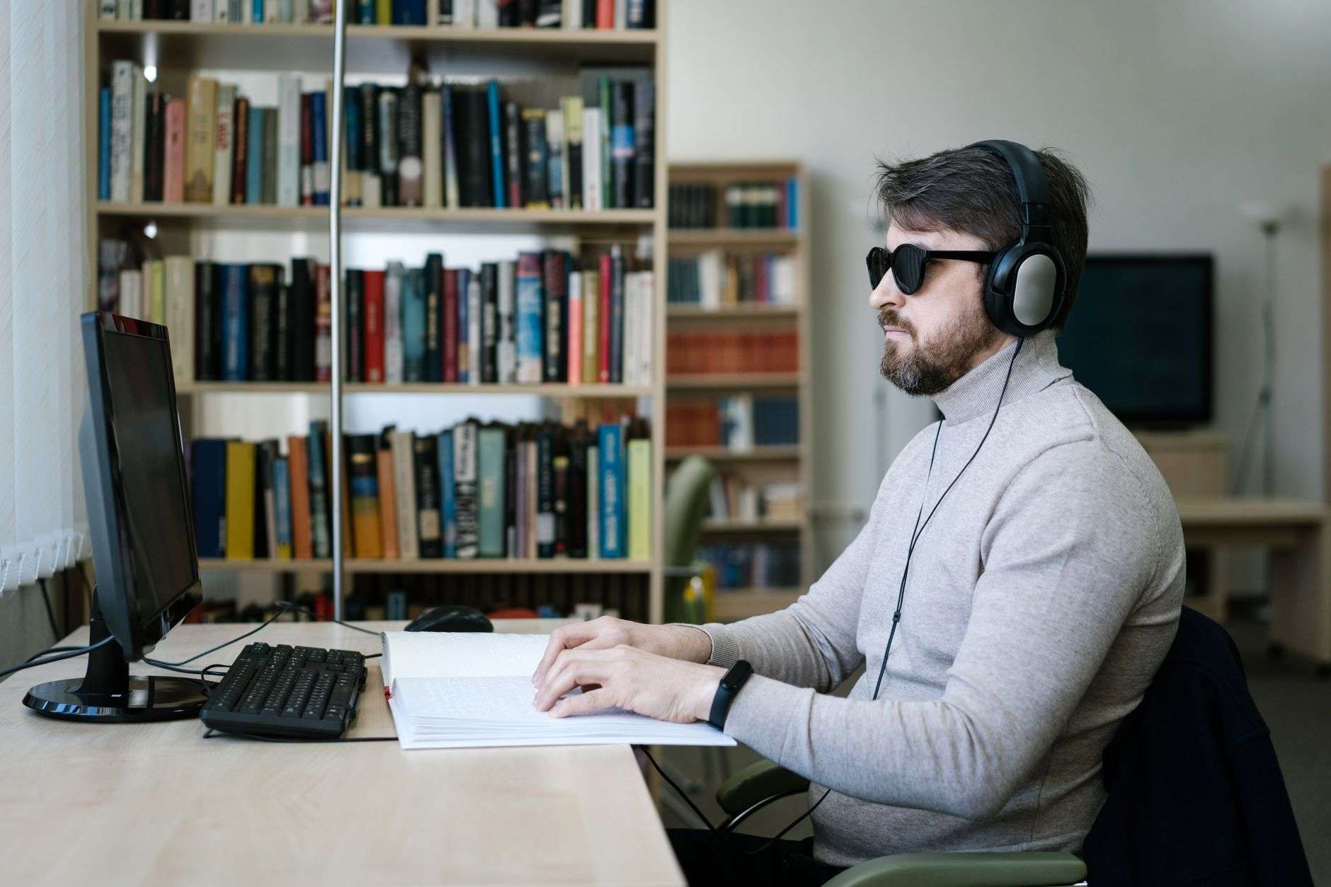 a blind man wearing headset while using braille