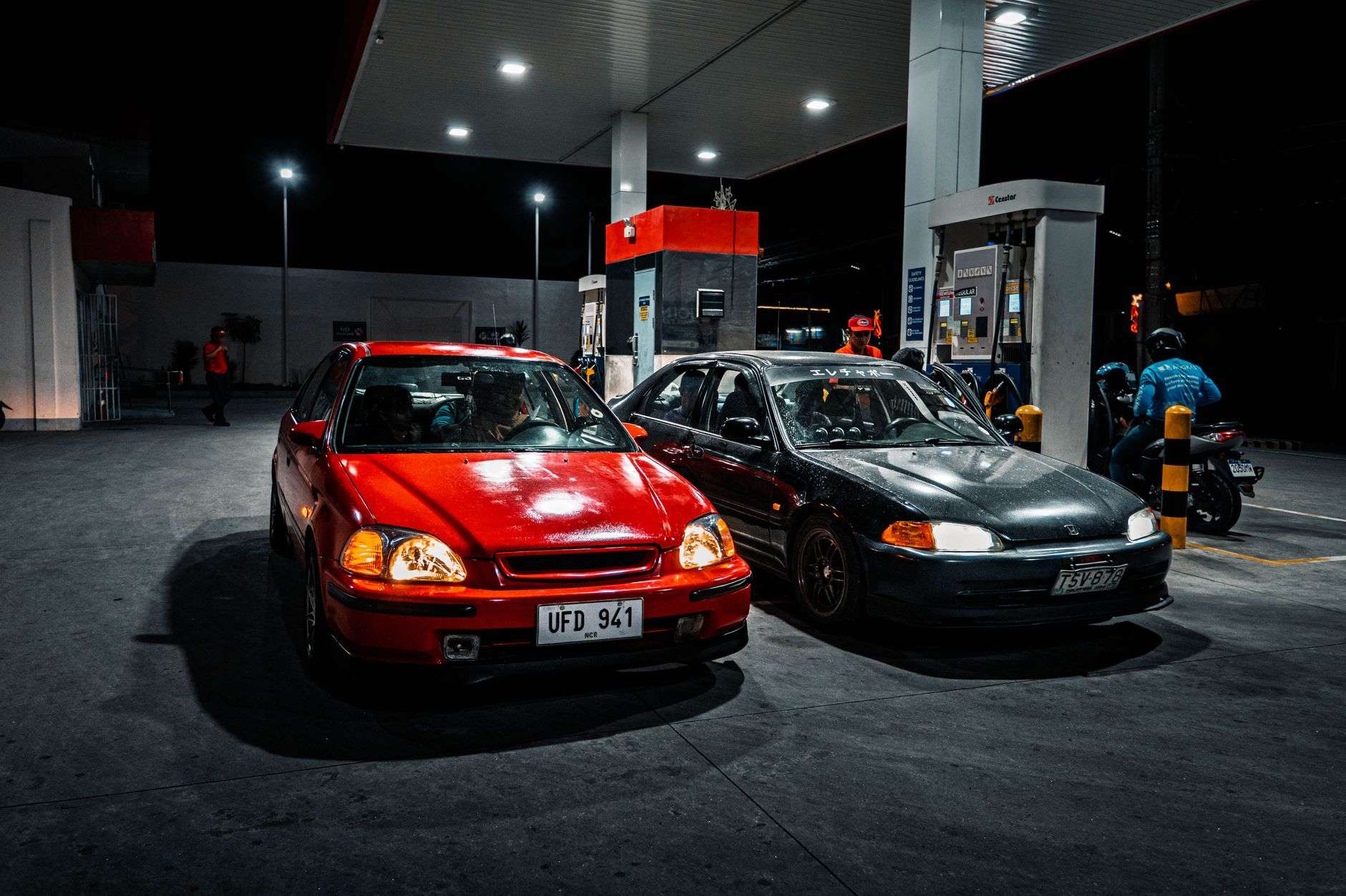 nighttime gas station scene with two cars