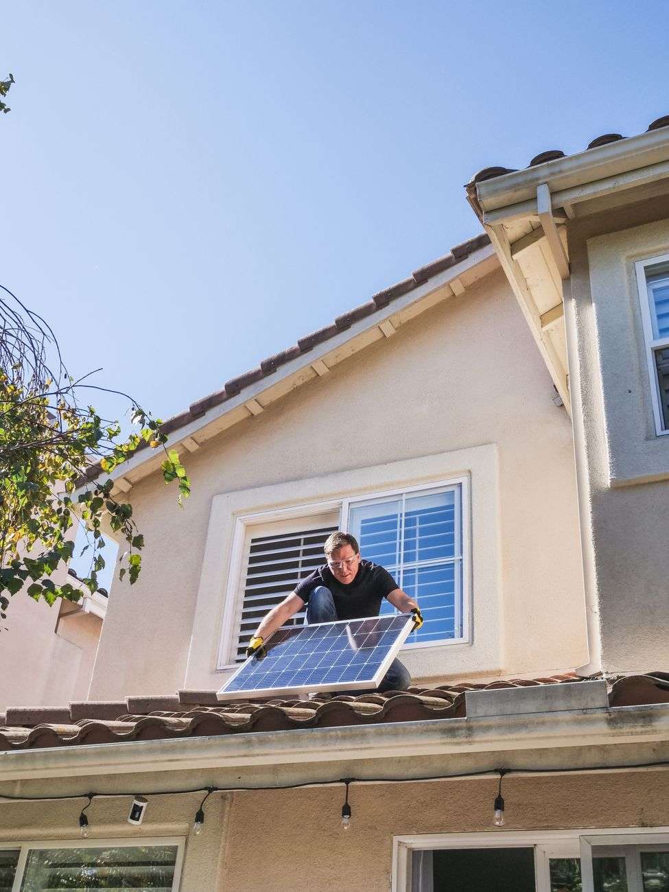 man in blue shirt and black pants sitting on roof